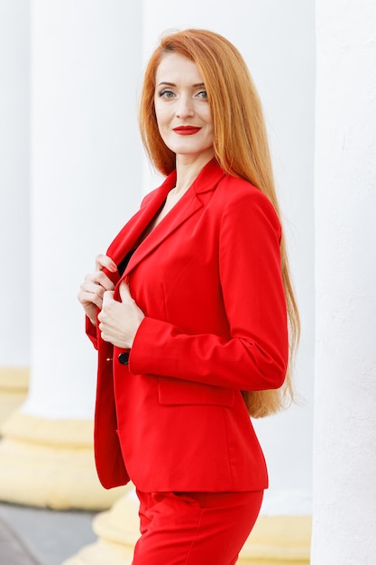 Красивая девушка с рыжими волосами, одетая в красный деловой костюм Деловой портрет