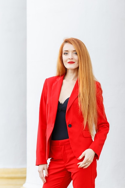 Beautiful girl with red hair dressed in a red business suit Business portrait