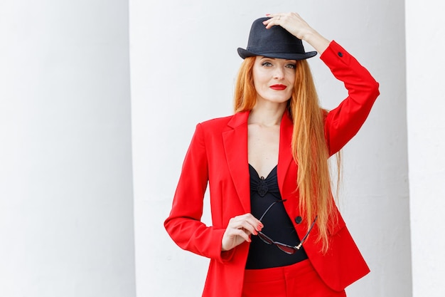 Beautiful girl with red hair dressed in a red business suit Business portrait