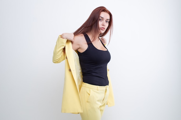 Beautiful girl with red hair posing in yellow business suit