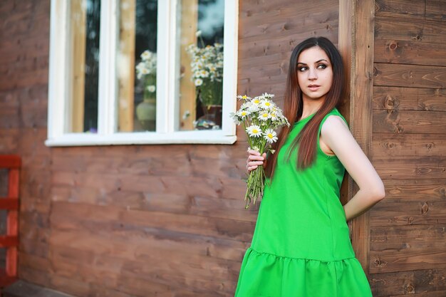 自宅の自然にヒナギクの花束と赤い髪の美しい少女