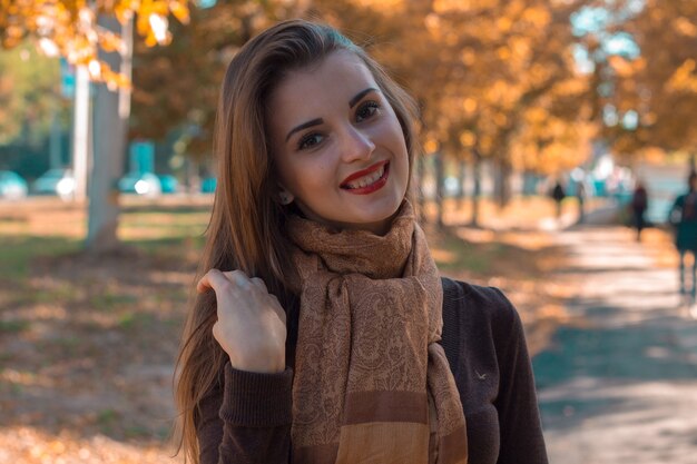 Beautiful girl with a scarf worth fall in the street and smiling closeup