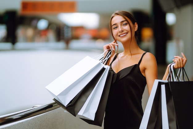 Beautiful girl with shopping bags looking at camera and smiling while doing shopping in the mall