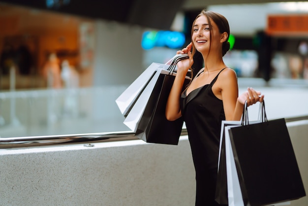 Beautiful girl with shopping bags looking at camera and smiling while doing shopping in the mall