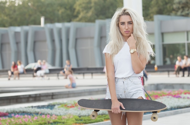 beautiful girl with skateboard. girl holding a skateboard in hands.