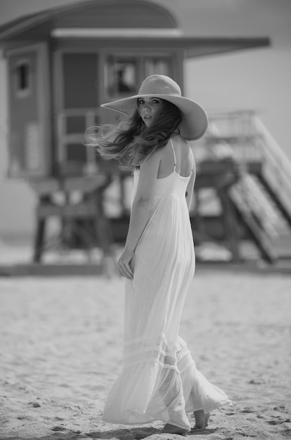 Beautiful girl with straw hat enjoying sunbath at beach young tanned woman enjoying breeze at seasid