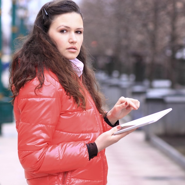 Beautiful girl with tablet in hands in the park talking on social networks