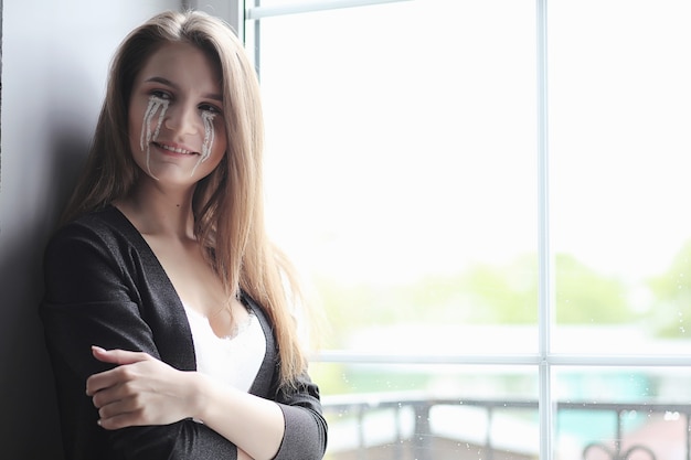 Beautiful girl with tears in eyes. Young girl with painted tears posing on camera. Girl for carnival with mask and makeup.