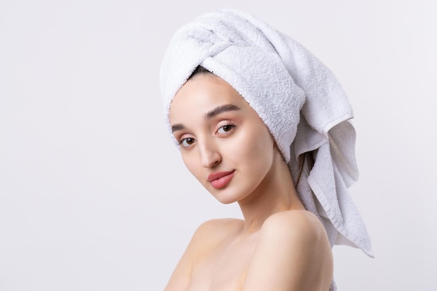Beautiful girl with thick eyebrows and perfect skin at white background towel on head beauty photo