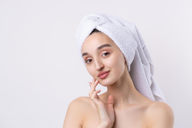 Beautiful girl with thick eyebrows and perfect skin at white\
background towel on head beauty photo