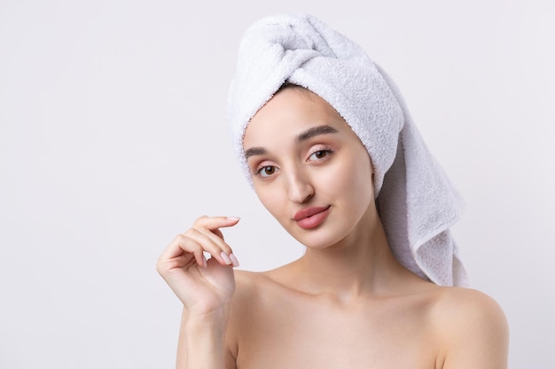 Beautiful girl with thick eyebrows and perfect skin at white background towel on head beauty photo