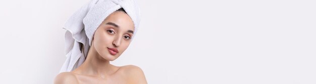 Beautiful girl with thick eyebrows and perfect skin at white background towel on head beauty photo