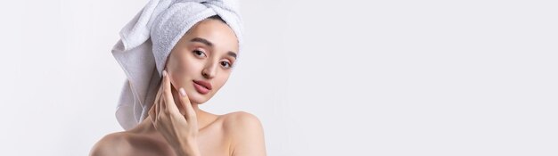 Beautiful girl with thick eyebrows and perfect skin at white background towel on head beauty photo