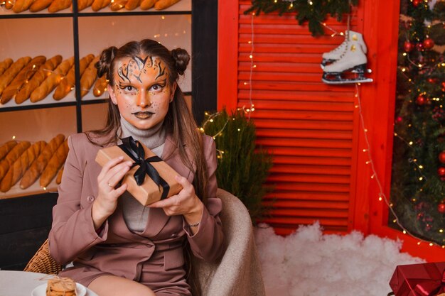 A beautiful girl with a tiger makeup rejoices at the gift new\
year concept year of the tiger