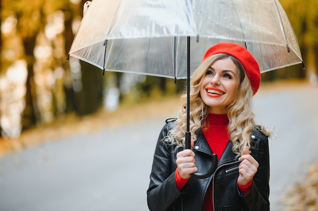 Beautiful girl with umbrella at autumn park.