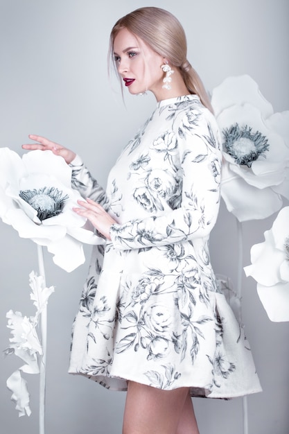 暖かい冬のウールのドレスでヴィンテージメイクと髪型の美しい少女。花の装飾。顔の美しさ。スタジオで撮影した写真