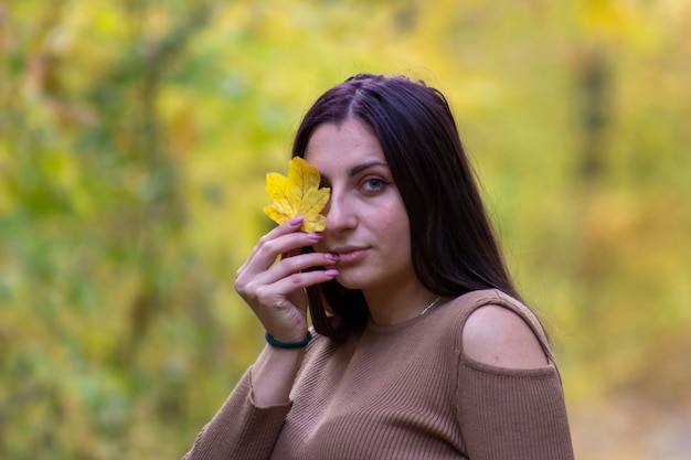 Beautiful girl with a yellow leaf near the face