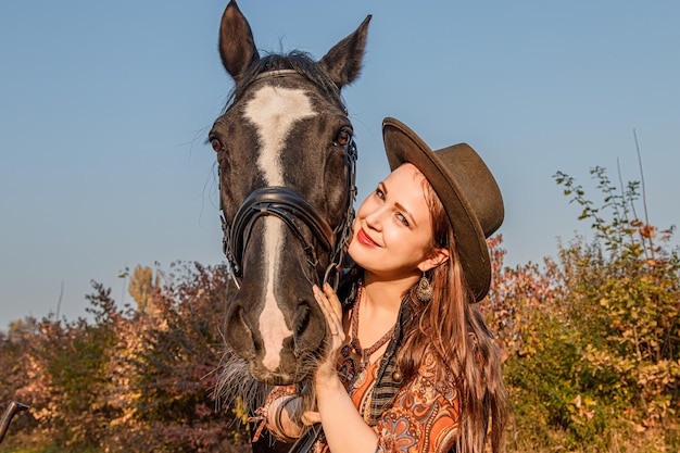 Beautiful girl a woman walks with a horse autumn road