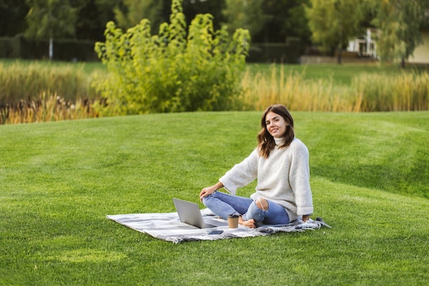 Beautiful girl working at a laptop in the park