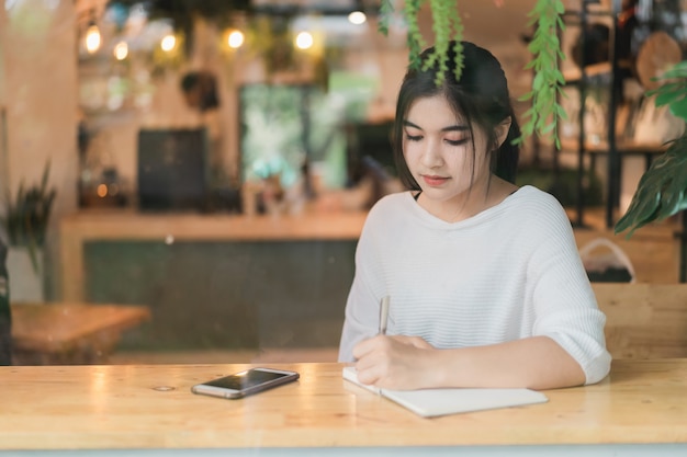 カフェのテーブルに取り組んでいる美しい少女