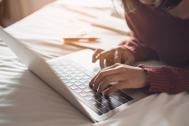 Foto bella ragazza che lavora con il computer portatile sul letto, lavora dal concetto di casa