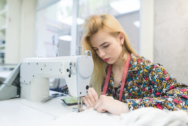 Beautiful girl works on a sewing machine.