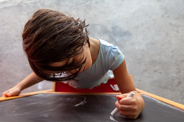 a beautiful girl writes on a blackboard with chalk