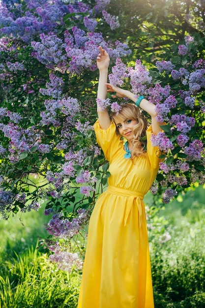 Beautiful girl in yellow dress in blooming garden