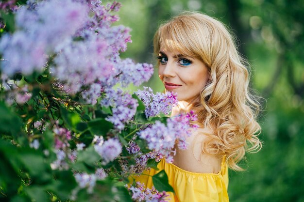 Foto bella ragazza in abito giallo in giardino fiorito