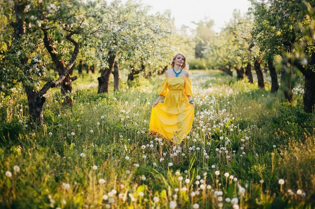 Beautiful girl in yellow dress in blooming garden