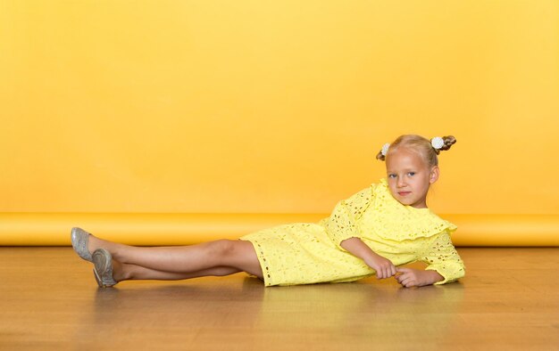 Beautiful girl in a yellow dress on a solid yellow background. Blonde with long hair. Emotions.