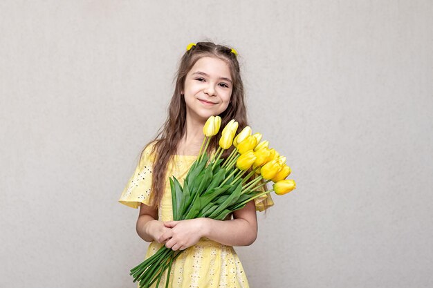 Beautiful girl in a yellow dress with yellow tulips in her hands Copy space