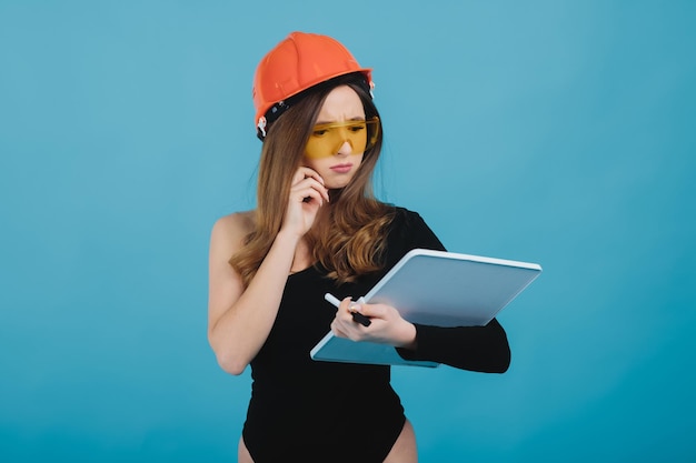 beautiful girl in yellow glasses and a protective helmet holds a white board in her hand