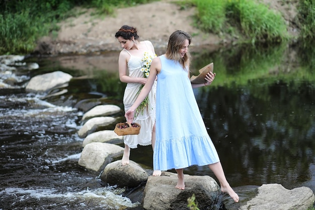 Beautiful girls in dresses on the river