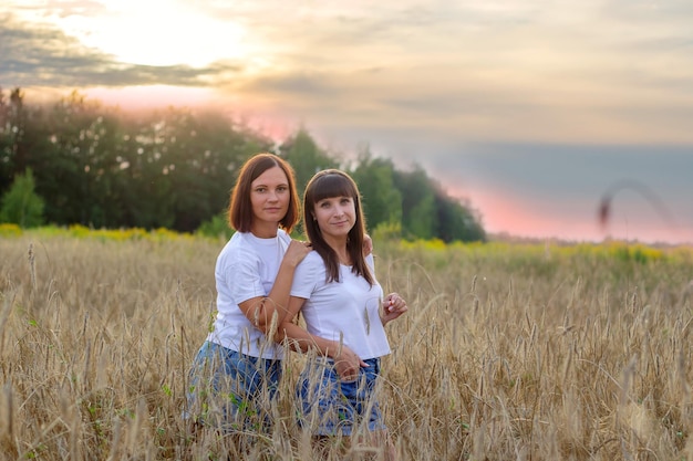 Photo beautiful girls in a field with wheat milk and bread peacetime happiness love two sisters girlfriends