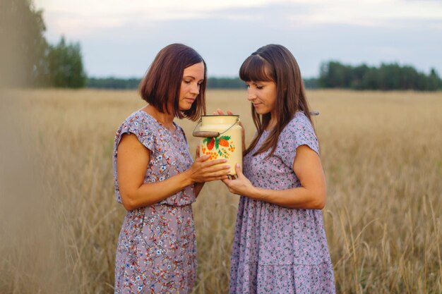 Beautiful girls in a field with wheat Milk and bread Peacetime Happiness Love Two sisters Girlfriends