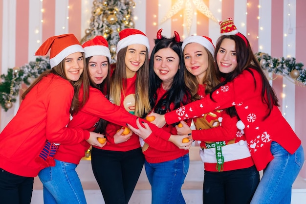 Beautiful girls hugging and looking at the camera Christmas tre