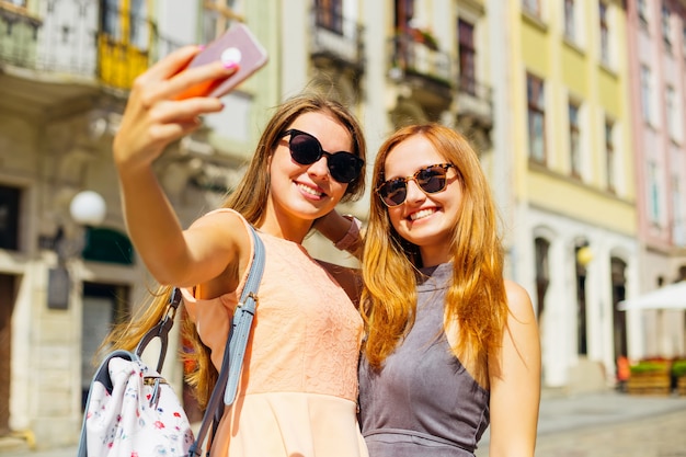 Beautiful girls on a sunny summer day make selfie against the background of the city