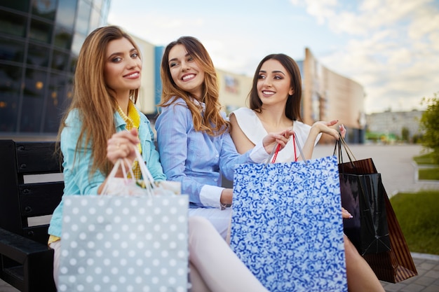 Foto belle ragazze con pacchetti dopo lo shopping una foto di un gruppo di amici felici che fanno shopping in città. ragazza che cammina per la città dopo lo shopping. buon umore. luce della sera. concetto di acquisto