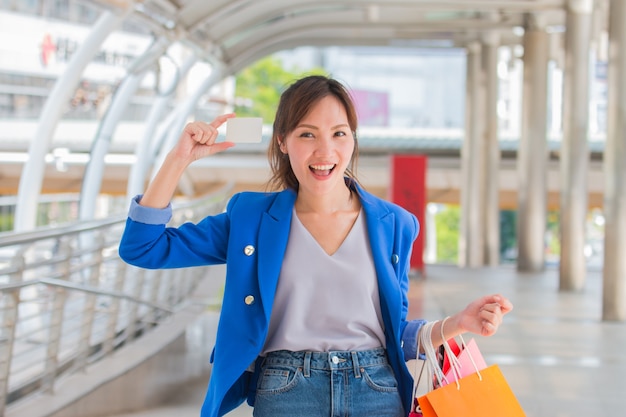 ショッピングバッグを持つ美しい女の子は、モールで買い物をしながら笑っています