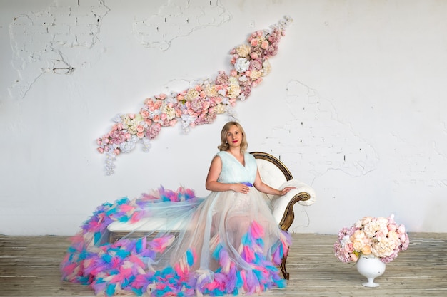 Foto bella donna incinta glamour in un vestito gonfio colorato è seduta sul divano buona gravidanza