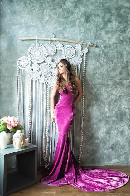 Красивая женщина фотомодели Glamourus в бархатном фиолетовом платье