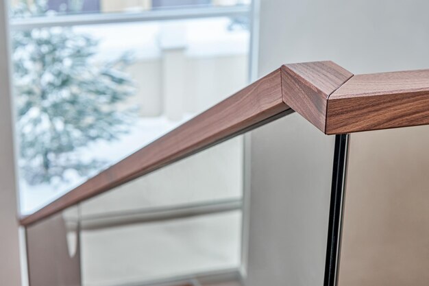 Beautiful glass railing of wooden staircase with wooden handrail in modern style