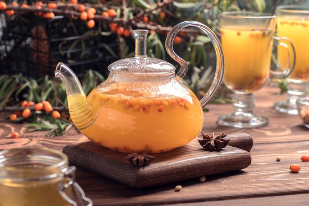 Beautiful glass teapot with sea buckthorn tea. Hot winter drinks.