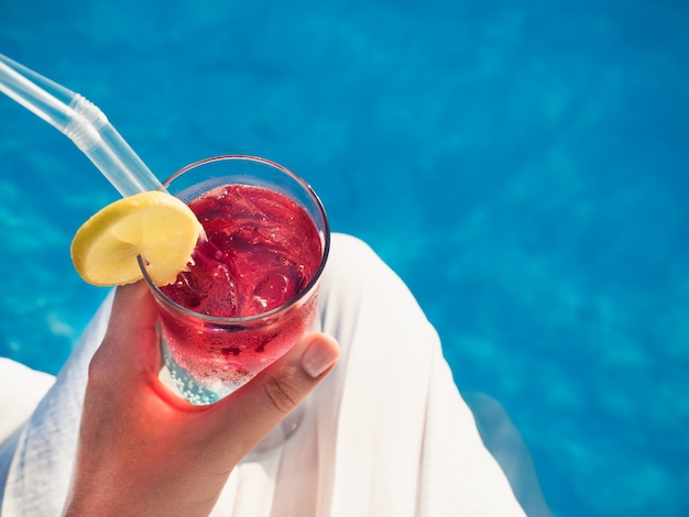 Beautiful glass with a cocktail on the background of the pool. Top view