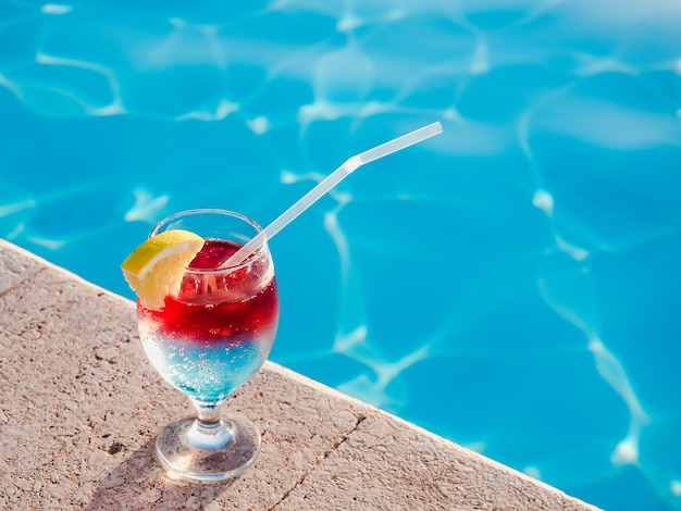 Beautiful glass with a cocktail next to pool