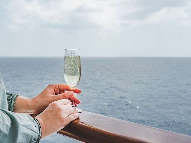 Beautiful glass with a drink on the background of sea waves and sun rays. Top view, close-up. Concept of leisure and travel