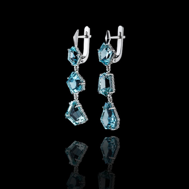 Beautiful gold earrings with aquamarine and diamonds on a black background