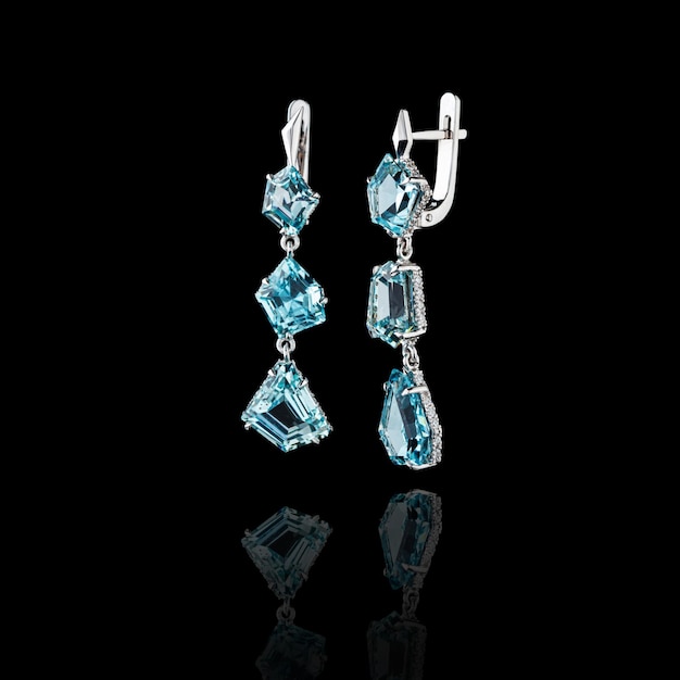 Beautiful gold earrings with aquamarine and diamonds on a black background