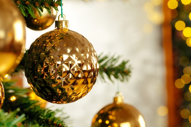 Beautiful golden bauble hanging from a Christmas tree